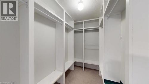 Walk-in closet featuring white built-in shelving, multiple hanging rods, and carpet flooring - 980 Creekside Drive, Waterloo, ON - Indoor With Storage