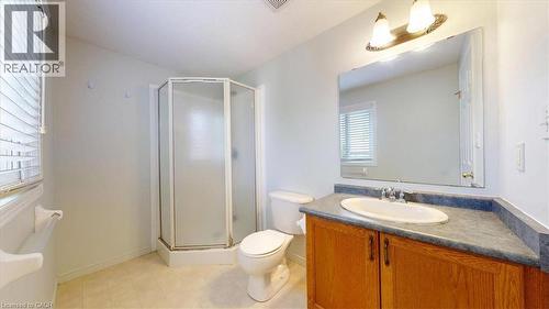Bathroom featuring a corner shower enclosure with frosted glass, a single vanity with wood-finish cabinetry, a white basin, a countertop, and an overhead vanity light fixture - 980 Creekside Drive, Waterloo, ON - Indoor Photo Showing Bathroom