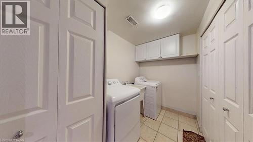 Dedicated laundry area featuring tile flooring, white shaker-style cabinetry, and an overhead light fixture - 980 Creekside Drive, Waterloo, ON - Indoor Photo Showing Laundry Room
