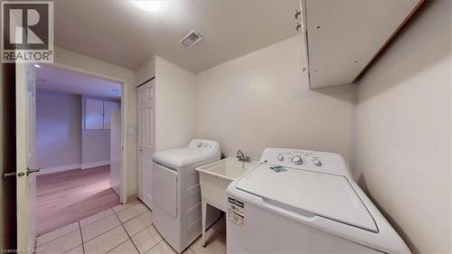 Dedicated laundry area featuring ceramic tile flooring, a utility sink with faucet, and overhead cabinetry - 980 Creekside Drive, Waterloo, ON - Indoor Photo Showing Laundry Room