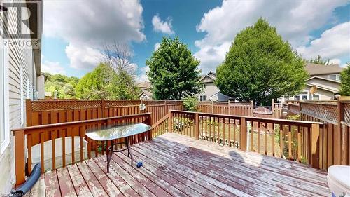Expansive wooden deck with railing and lattice detailing, overlooking a fenced backyard with mature trees - 980 Creekside Drive, Waterloo, ON - Outdoor With Deck Patio Veranda With Exterior