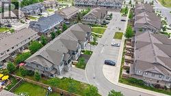 Row of townhomes featuring grey siding and stone accents, individual balconies, and private rear yards with wood fencing - 