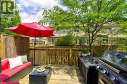 Multi-level wood-finish deck featuring wood privacy fencing, built-in outdoor cabinetry, and mature perimeter trees - 