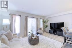 Open-concept living area featuring light wood-finish flooring, recessed lighting, and ample natural light from multiple windows - 
