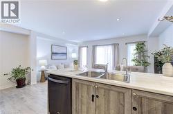 Kitchen island featuring a double basin stainless steel sink with a high-arc faucet, wood-finish cabinetry, and light-toned countertops - 
