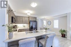 Open-concept kitchen featuring wood-finish cabinetry, stainless steel sink, and a large central island with seating - 
