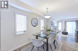 Open-concept dining area featuring wood-finish flooring, a contemporary chandelier, and a large window with blinds - 