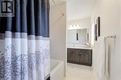 Bathroom featuring a white bathtub, light-toned wall tiling, dark wood-finish vanity with white countertop, and a mirrored medicine cabinet - 