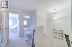 Upper-level hallway featuring carpet flooring, crisp white walls, recessed panel doors, and a semi-flush mount ceiling fixture - 