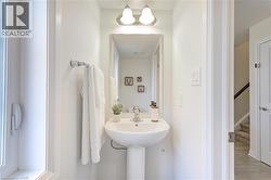 Pedestal sink with chrome faucet, complemented by a rectangular framed mirror and wall-mounted light fixture - 