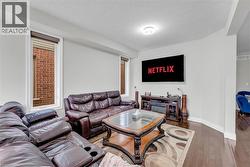 Living area featuring dark wood-finish flooring, light-toned walls, and multiple windows with brown roller shades - 