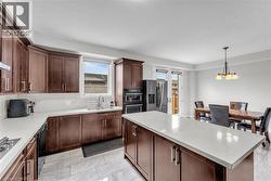Gourmet kitchen featuring rich wood cabinetry, light-toned countertops, a full suite of stainless steel appliances, and a central island with countertop seating - 
