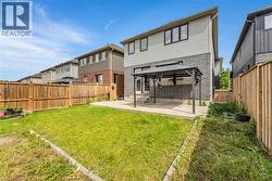 Expansive grassy yard area with a concrete patio featuring a metal gazebo structure - 