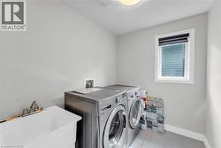 Dedicated laundry room featuring a utility sink with faucet, a window providing natural light, and tile flooring - 