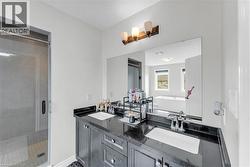 Bathroom featuring a dual vanity with dark cabinetry, integrated sinks, and a large wall mirror - 