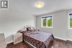 Bright room featuring two windows, wood-finish flooring, white baseboards, and a flush mount ceiling light - 