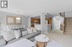 Light gray wall paint throughout, light-toned carpeting, and a wooden staircase with white balusters - 