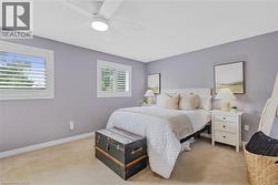 Bedroom featuring neutral-toned carpeting, light purple walls, and white trim - 