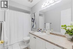 Bathroom featuring a shower/tub combination with white shower curtain, white vanity with integrated sink, beige countertop, and an expansive wall-mounted mirror - 