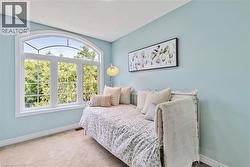Spacious room featuring a large arched window with white framing, light blue wall finishes, white baseboards, and neutral carpet flooring - 