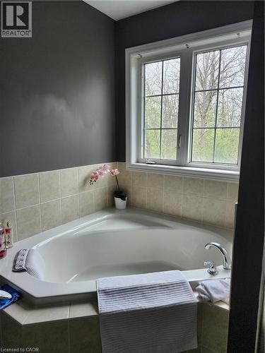 Corner soaking tub with tiled surround, chrome fixtures, and a multi-pane window - 249 Bussel Crescent, Milton, ON 