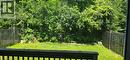 Private backyard featuring a manicured lawn, wood fencing, and dense mature trees providing natural screening - 249 Bussel Crescent, Milton, ON 