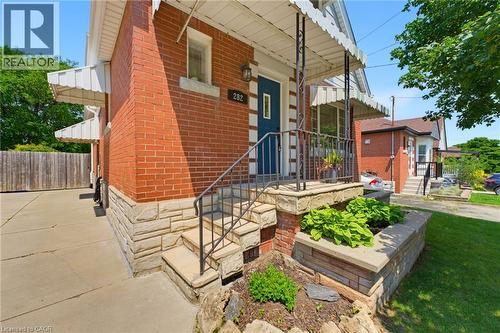 Red brick exterior with stone veneer accents, a blue front entry door, and a concrete driveway - 282 East 13Th Street, Hamilton, ON 