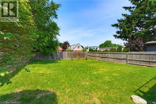 Expansive backyard featuring a manicured lawn, established perimeter fencing, and mature trees providing natural shade - 282 East 13Th Street, Hamilton, ON 