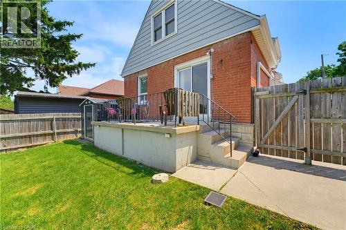 Red brick exterior featuring light blue siding and a raised concrete patio - 282 East 13Th Street, Hamilton, ON 