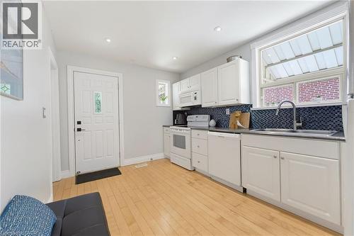 Kitchen featuring white cabinetry, a dark countertop, and a blue mosaic tile backsplash - 282 East 13Th Street, Hamilton, ON 
