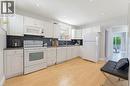 Bright kitchen featuring light wood-finish flooring, white cabinetry, dark countertops, and a blue mosaic tile backsplash - 282 East 13Th Street, Hamilton, ON  - Indoor Photo Showing Kitchen 