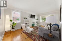 Living area featuring wood-finish flooring, a white-painted stone fireplace surround, and built-in shelving - 