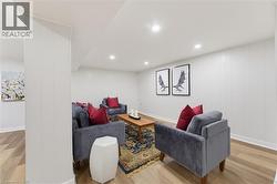 Brightly lit living space featuring recessed lighting, wood-finish flooring, and white paneled walls - 