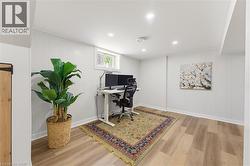 Recessed lighting illuminates this versatile room, featuring a window, paneling on walls, and wood-finish flooring - 