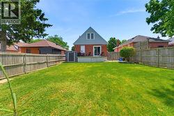 Expansive fenced backyard featuring a large green lawn, concrete patio, and a storage shed - 