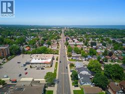 Aerial perspective showcasing a residential neighborhood with mature tree coverage, a prominent central thoroughfare, and a commercial building with an expansive parking lot - 