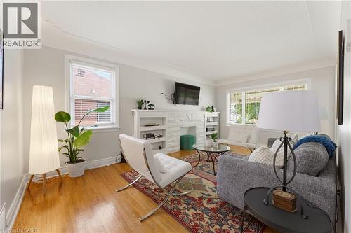Living area featuring wood-finish flooring, a white-painted stone fireplace surround, and built-in shelving - 282 East 13Th Street, Hamilton, ON 