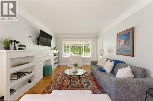 Spacious living area featuring wood-finish flooring, a white stone-finish fireplace, and built-in shelving - 282 East 13Th Street, Hamilton, ON 