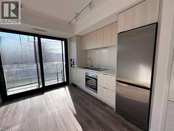 Kitchen with light wood-finish cabinetry, stainless steel appliances, and a built-in oven - 