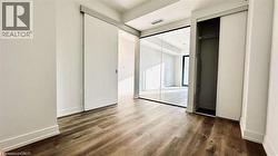 Wood-finish flooring throughout, featuring a modern sliding barn door, mirrored wall panels, and a built-in closet with sliding doors and interior hanging rod - 