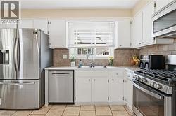 Well-appointed kitchen featuring white cabinetry, light-toned countertops, and a tiled backsplash - 