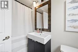 Contemporary bathroom featuring a rectangular vessel sink, dark wood-finish vanity, and a framed mirror with integrated lighting - 