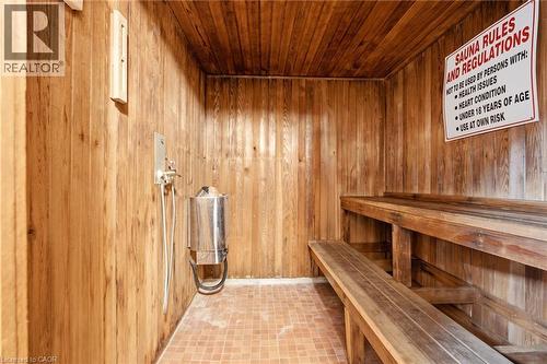 Wood-paneled sauna featuring tiered wood benches, a wall-mounted heater, and tiled flooring - 15 Nicklaus Drive Unit# 17, Hamilton, ON 