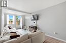 Spacious living area featuring light-toned walls, wood-finish flooring, and a large window providing outdoor access - 15 Nicklaus Drive Unit# 17, Hamilton, ON 