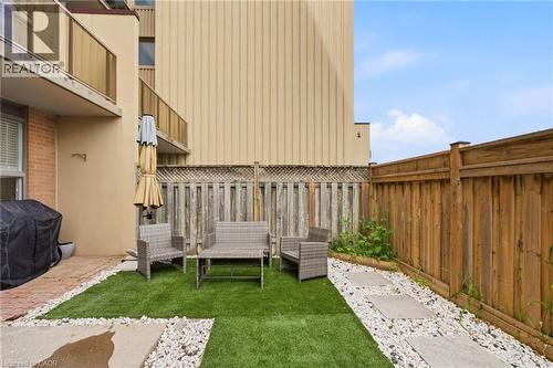 Patio area featuring artificial turf, a stone pathway with white gravel, and a full privacy fence - 15 Nicklaus Drive Unit# 17, Hamilton, ON 