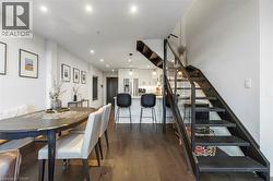 Open-concept living space featuring wood-finish flooring, recessed lighting, and a modern staircase with a glass and metal railing - 