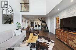 Spacious living area featuring high ceilings, wood-finish flooring, and a stacked stone accent wall - 
