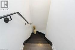 Staircase featuring dark wood-finish treads, a black handrail, and white painted walls - 