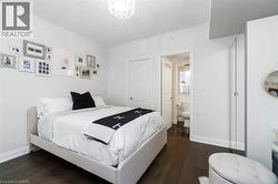 Bedroom featuring dark wood-finish flooring, white walls, and a contemporary ceiling fixture - 