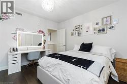 Bedroom featuring dark wood-finish flooring and a white ceiling with a decorative light fixture - 